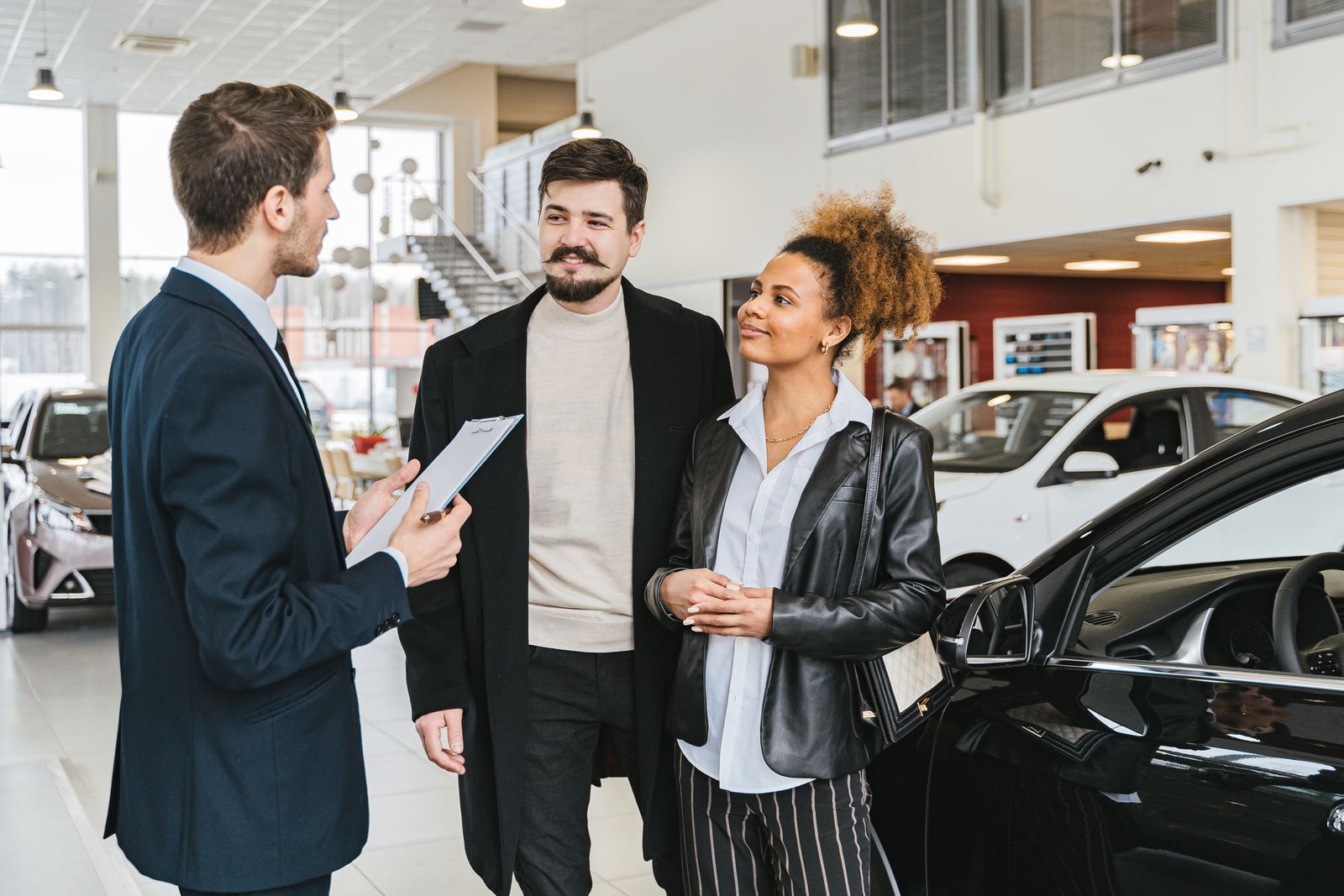Car dealership salesperson helping a couple in the showroom