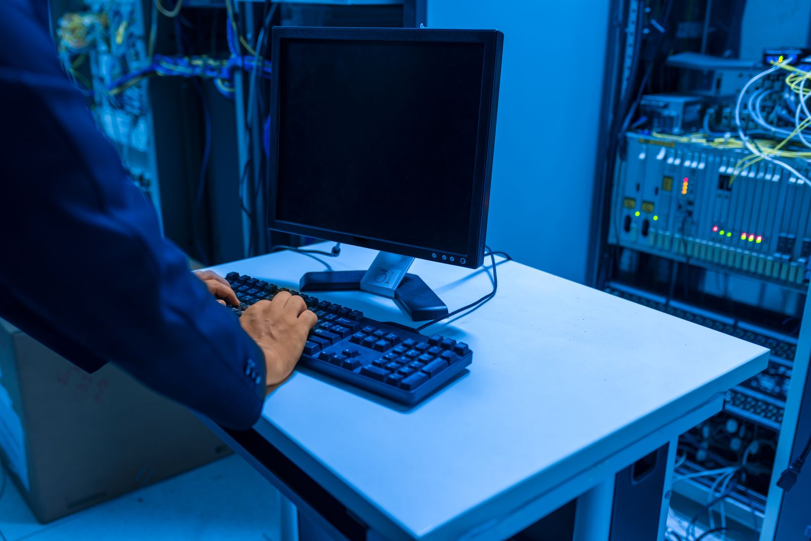 IT technician working at a console between network server racks