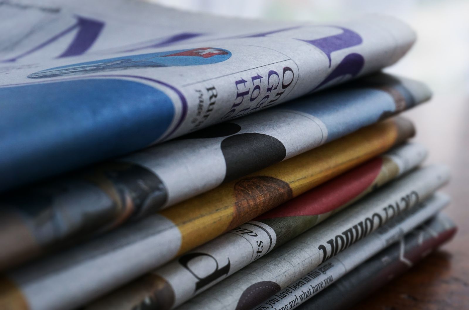 Stack of freshly printed newspapers and magazines on a wooden table