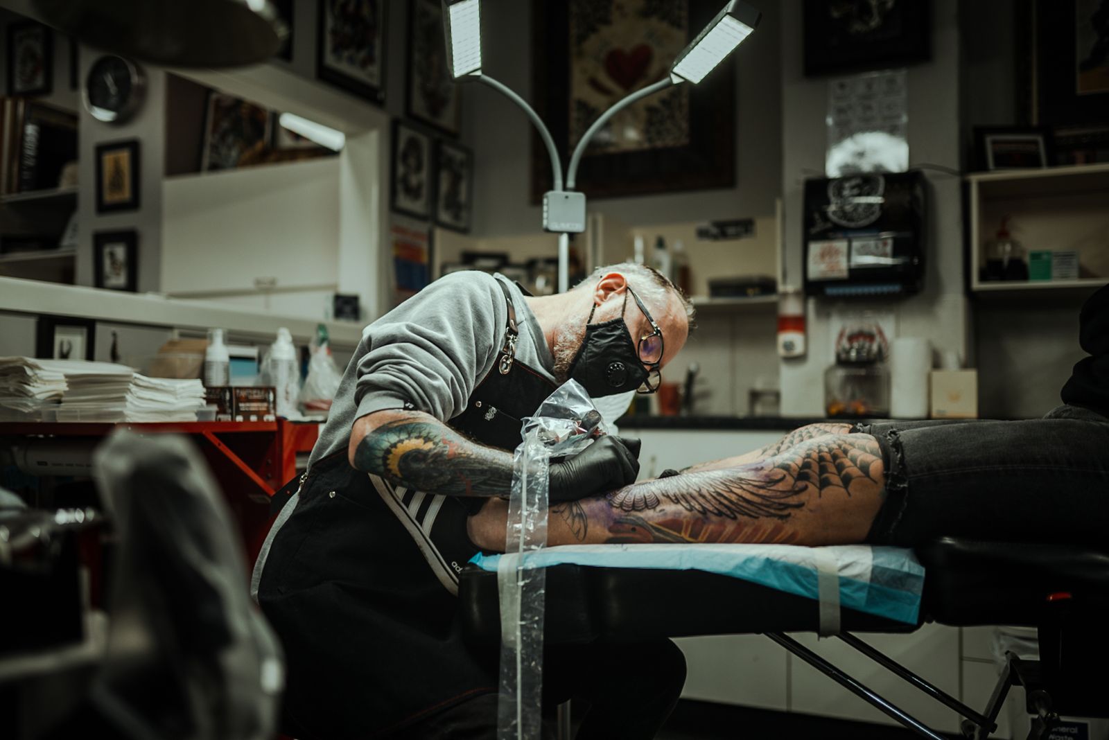 Tattoo artist working on a client's leg in the studio